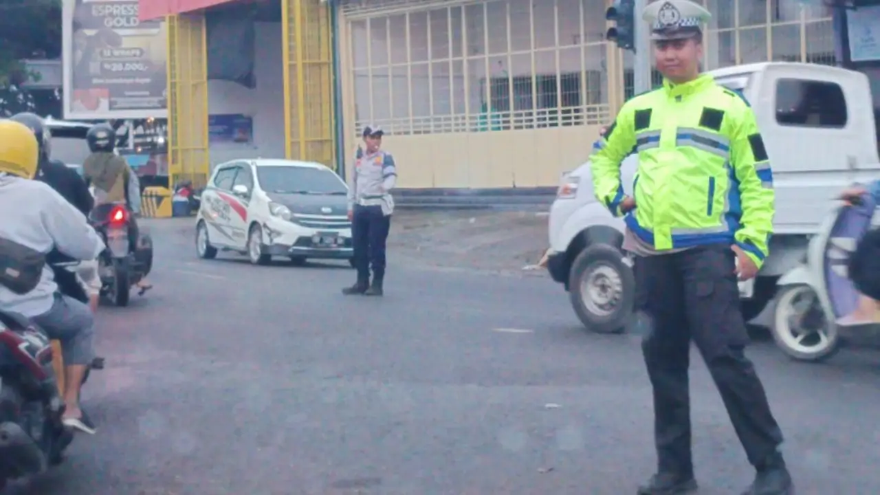 Polisi lalulintas Polres Bulukumba tetap semangat mengatur arus kendaraan saat hujan deras di pertigaan Lajae.