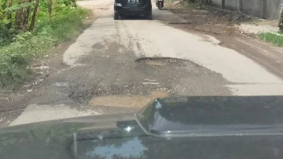 Pekerja melakukan penambalan jalan poros Bulukumba–Sinjai yang rusak