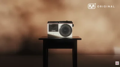 Platform konten Mnet, Mnet Plus, merilis sebuah teaser video bertajuk “2026 COMING SOON” pada 1 Januari 2026.