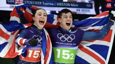 Pasangan Inggris Tabitha Stoecker dan Matt Weston merayakan emas skeleton beregu setelah mencetak rekor lintasan di Olimpiade Milan–Cortina. Foto @ArchiveInt