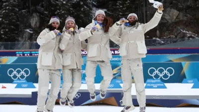 Julia Simon melintasi garis finis sambil membawa bendera Prancis usai memastikan emas estafet biathlon putri.