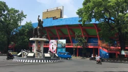 Stadion Gajayana Kota Malang dengan tugu patung di bundaran dan pengendara sepeda motor melintas