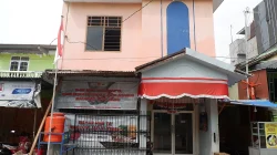 Bangunan dua lantai bercat merah muda dengan kanopi merah putih dan spanduk Makassar cinta damai di Kelurahan Tallo