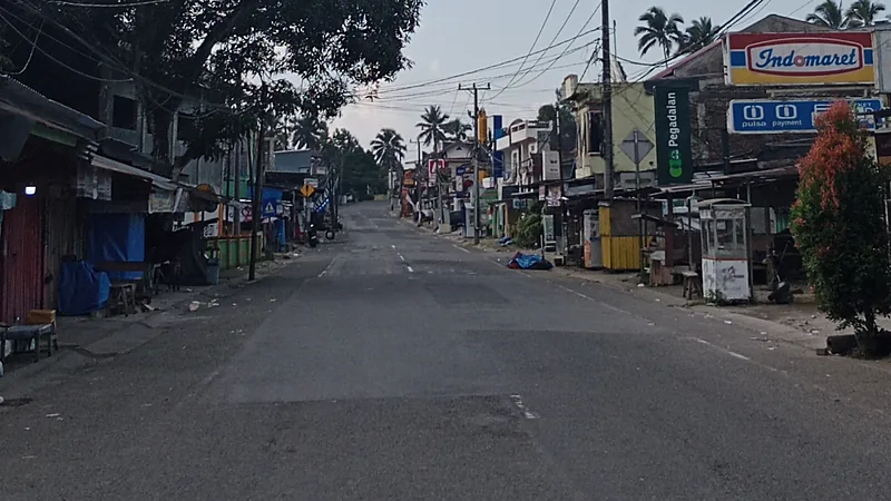 Ruas jalan poros di Bulukumba pada pagi hari dengan deretan ruko dan kios di kedua sisi