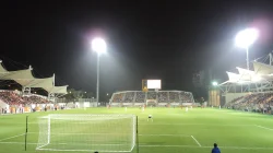 Pertandingan sepak bola malam hari di Stadion Mong Kok Hong Kong dengan tiga tribune dan lampu sorot menyala