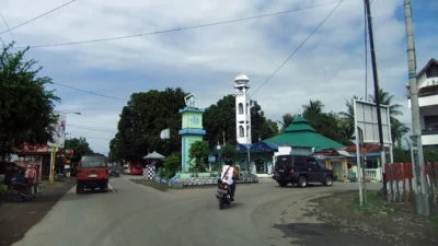Jalan raya di Kabupaten Bulukumba dengan tugu berbentuk perahu pinisi dan menara masjid di sisi kanan