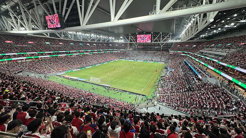 Tribune Stadion Kai Tak Hong Kong terisi penuh penonton saat pertandingan sepak bola malam hari
