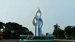 Monumen Arek Lancor di Pamekasan berupa tugu putih bergelombang menjulang di atas taman berpagar hijau