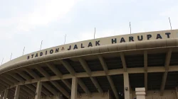 Bagian atap tribun Stadion Si Jalak Harupat bercat krem dengan huruf besar bertuliskan Stadion Jalak Harupat di bawah langit berawan