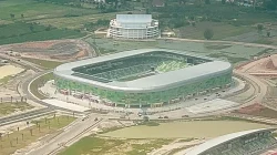 Foto udara Stadion Utama Sumatera Utara berfasad hijau dengan atap perak, dikelilingi lahan kosong dan jalan melingkar