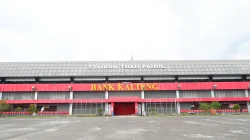Fasad Stadion Tuah Pahoe dengan papan nama stadion dan pintu merah di pelataran kosong