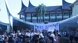 Kerumunan jurnalis berunjuk rasa membentangkan spanduk bertuliskan Pers Sumbar, barisan polisi berdiri di belakang