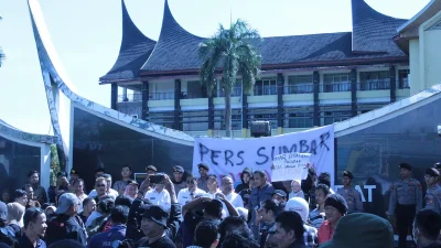 Kerumunan jurnalis berunjuk rasa membentangkan spanduk bertuliskan Pers Sumbar, barisan polisi berdiri di belakang