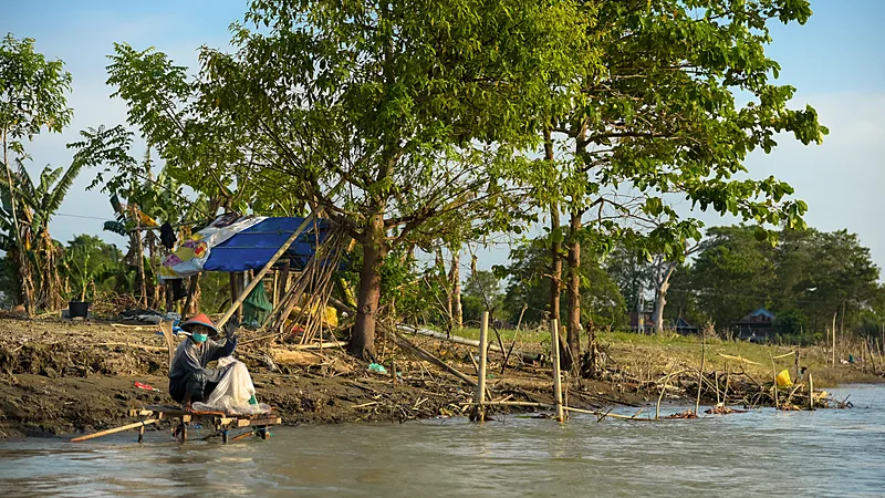 Kekeringan Landa 13 Kecamatan di Wajo, BPBD Salurkan 303.000 Liter Air Seorang warga bertopi duduk di bangku kayu di tepi Danau Tempe yang airnya dangkal, dengan pepohonan di belakangnya
