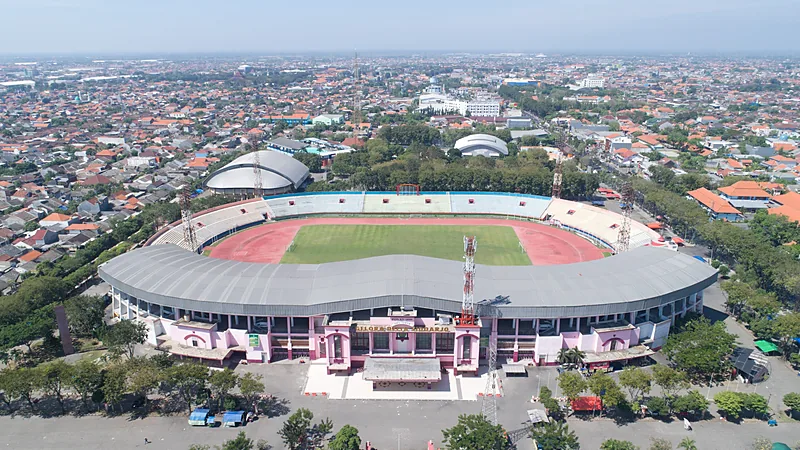 Foto udara Stadion Gelora Delta Sidoarjo dengan atap abu-abu melengkung, lapangan hijau, dan lintasan merah di tengah permukiman padat