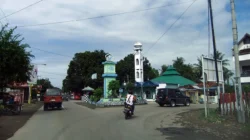 Jalan raya di Kabupaten Bulukumba dengan tugu berbentuk perahu pinisi dan menara masjid di sisi kanan