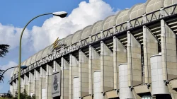 Fasad Estadio Santiago Bernabéu dengan tulisan nama stadion dan atap melengkung di bawah langit biru