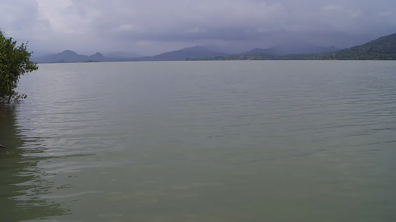 Permukaan air Waduk Bili-Bili yang luas dengan pegunungan di kejauhan dan langit mendung