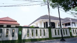Deretan bangunan pengadilan beratap genteng di balik pagar tembok putih berlis hijau, dengan papan nama gedung terbaca sebagian di bagian belakang