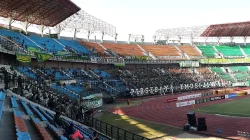 Tribun Stadion Gelora Bung Tomo dipenuhi suporter Persebaya berbaju hijau dengan spanduk bertuliskan Persebaya Emosi Jiwaku