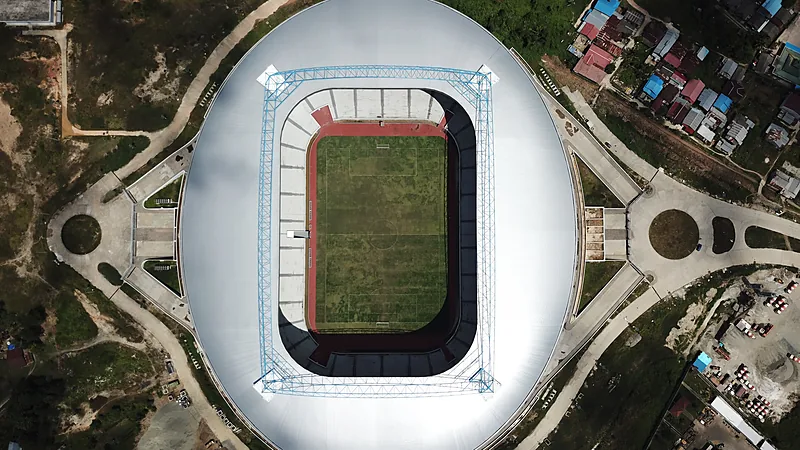 Foto udara Stadion Batakan dengan atap putih melingkar dan lapangan hijau di tengah lahan terbuka