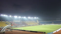 Stadion Si Jalak Harupat pada malam hari dengan lampu sorot menyala di atas tribun kuning dan merah serta lapangan hijau yang lengang