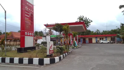 SPBU Pertamina dengan papan harga Pertamax 92, Pertalite, Solar, dan Dexlite serta mobil putih di area pengisian