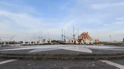 Huruf besar bertuliskan Pantai Losari di anjungan dengan kapal pinisi dan Masjid 99 Kubah di latar belakang
