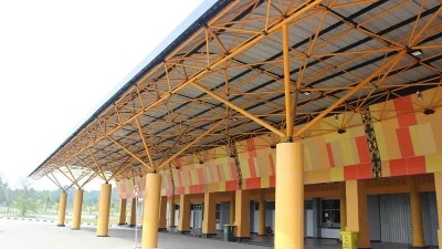 Kanopi kuning Stadion Kaharuddin Nasution Pekanbaru dengan pilar oranye di area pintu masuk