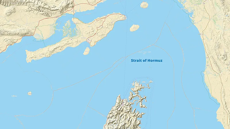 Peta topografi Selat Hormuz bertuliskan Strait of Hormuz di tengah perairan biru, menampilkan garis pantai Iran di utara, Semenanjung Musandam di selatan, serta garis putus-putus jalur pelayaran