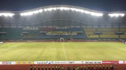 Stadion Patriot Candrabhaga dengan lampu atap menyala dan petugas berbaris di lintasan lari