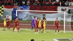 Pemain Timnas Indonesia berseragam merah bersiaga di depan gawang menghadapi pemain Brunei berseragam kuning, dengan spanduk suporter di tribun belakang