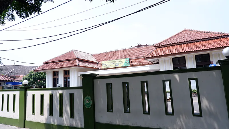 Tikam Eks Mertua di Caile, Terdakwa Diperiksa 24 September Gedung pengadilan beratap genteng merah di balik pagar tembok putih-hijau bercelah vertikal dengan logo lembaga peradilan