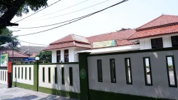 Bangunan pengadilan beratap genteng merah di balik pagar tembok berlis hijau, dengan papan nama layanan pengadilan terpasang di dinding