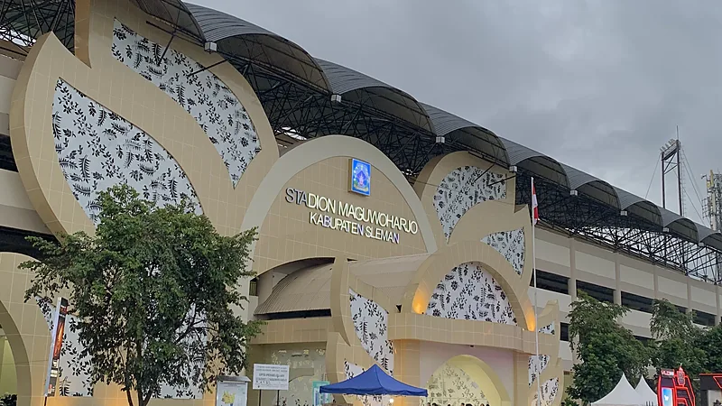 Gerbang Stadion Maguwoharjo Kabupaten Sleman dengan ornamen krem bermotif dan rangka atap tribun di belakangnya