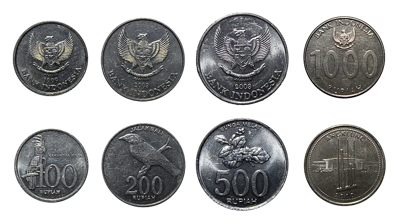 Delapan keping uang logam rupiah pecahan seratus, dua ratus, lima ratus, dan seribu rupiah bergambar garuda, burung jalak bali, serta bunga melati, disusun dua baris di latar putih