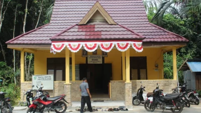 Kantor kepala desa bercat kuning dengan umbul-umbul merah putih dan sepeda motor terparkir di halaman