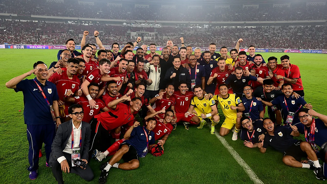 Skuad timnas Indonesia berkaus merah dan ofisial berfoto bersama di tengah lapangan stadion yang penuh penonton