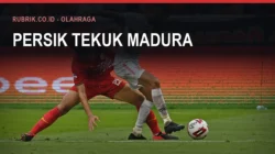 Dua pemain sepak bola berebut bola di dekat garis lapangan dalam laga Liga Indonesia, dengan teks judul "Persik Tekuk Madura" dan label Rubrik.co.id - Olahraga di bagian atas gambar