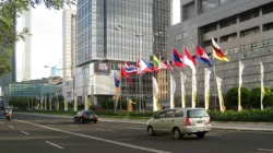 Deretan bendera negara anggota ASEAN berkibar di tepi jalan protokol Jakarta dengan gedung bertingkat di latar belakang